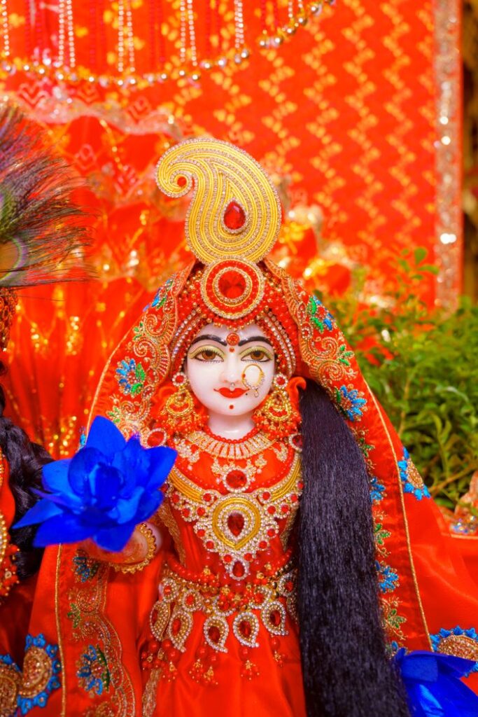 Vibrant Hindu deity statue with intricate decorations and blue flower in Vrindavan, India.