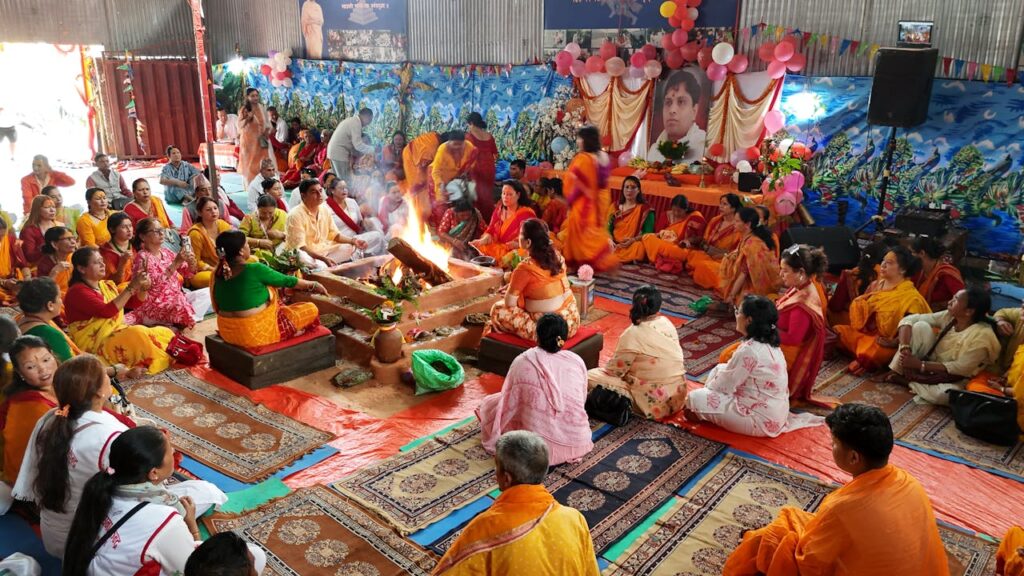A traditional Indian indoor ceremony featuring a sacred fire ritual with participants in colorful attire.