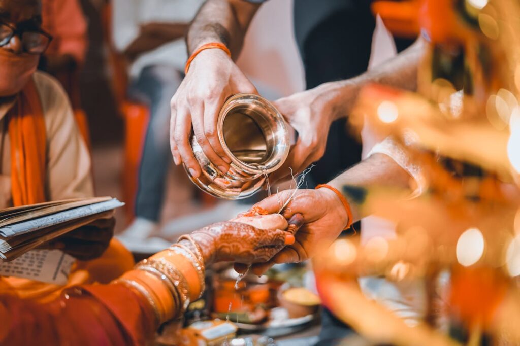 Close-up of traditional Indian wedding ritual pouring sacred water hands, highlighting cultural details.